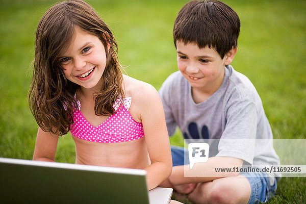 Kinder benutzen Laptop im Freien