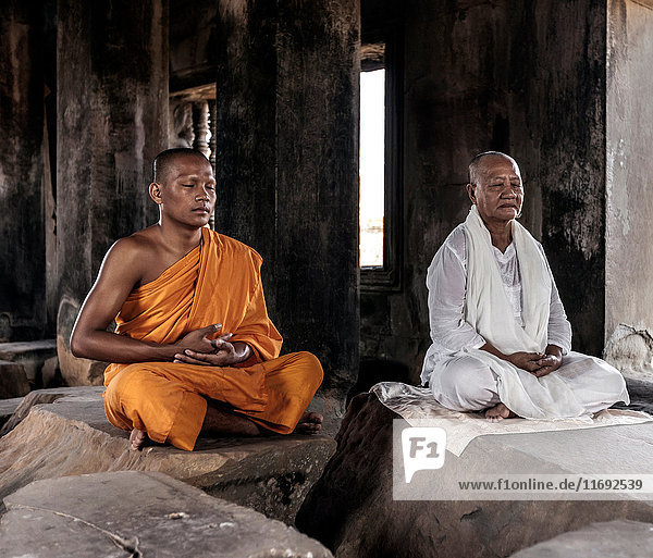 Senior and young monk meditating in temple in Angkor Wat  Siem Reap  Cambodia
