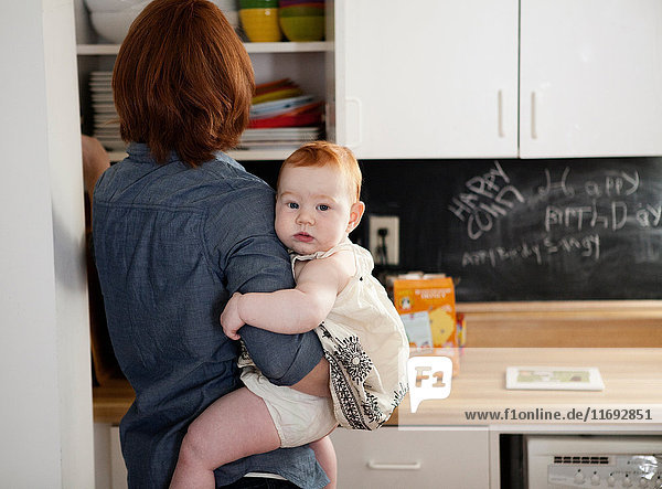 Mother holding baby daughter in kitchen