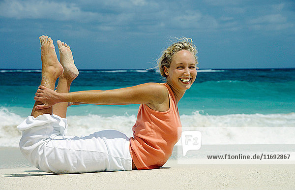 Frau praktiziert Yoga am tropischen Strand