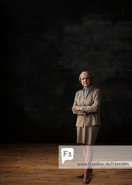 Portrait of businesswoman standing by blackboard
