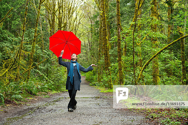 Frau auf Waldweg mit rotem Regenschirm