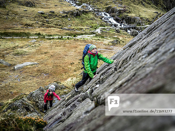 Hikers scaling steep rock face