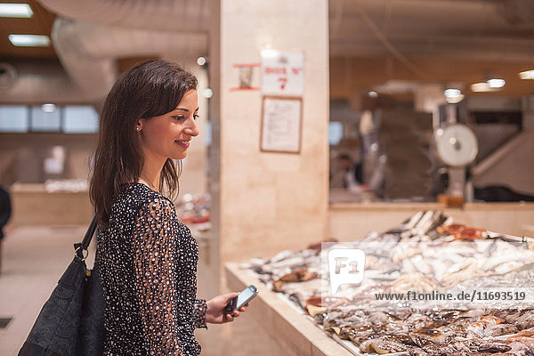 Frau betrachtet frischen Fisch auf dem Markt