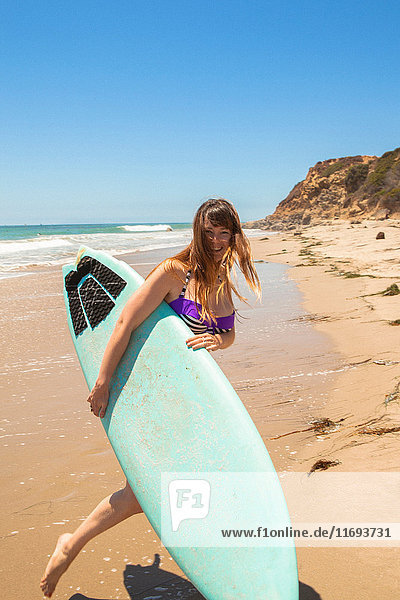 Junge Frau am Strand mit Surfbrett