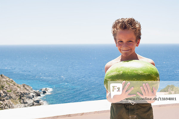 Boy holding watermelon on balcony