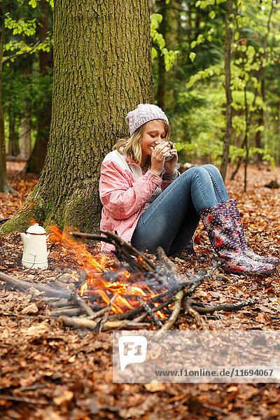 Woman drinking coffee by campfire