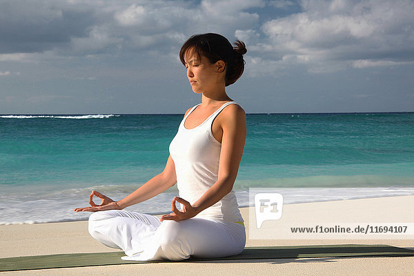 Frau meditiert an tropischem Strand