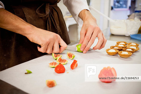 Baker slicing fruit in kitchen