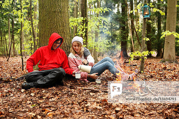 Couple drinking coffee by campfire