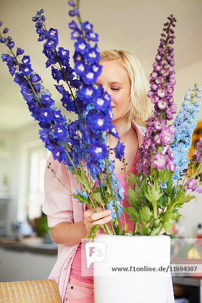 Woman arranging flowers in kitchen