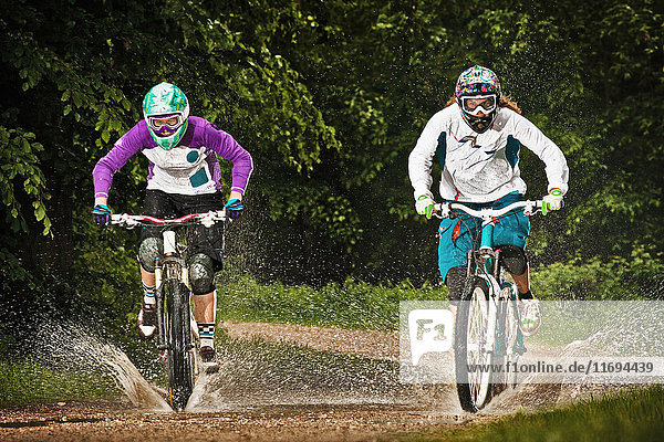 Zwei Mountainbikerinnen fahren durchs Wasser