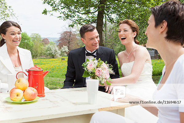 Newlywed couple at table with friends
