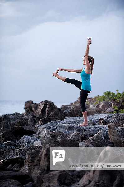 Frau praktiziert Yoga auf einer Felsformation