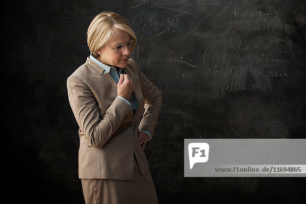 Portrait of businesswoman by blackboard