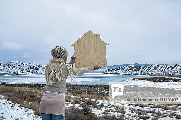 Frau in malerischer Landschaft mit Holzform eines Hauses