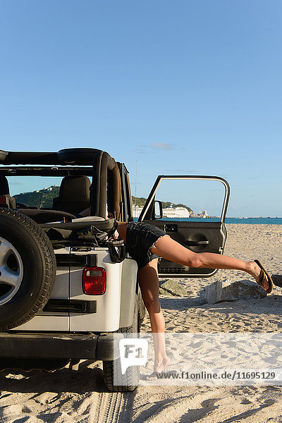 Woman searching in jeep on beach