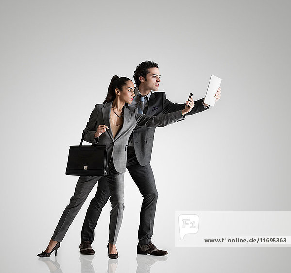Business couple using cell phone and digital tablet