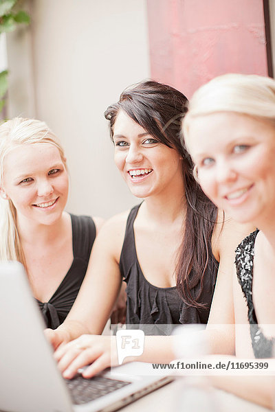 Lächelnde Frauen benutzen gemeinsam einen Laptop
