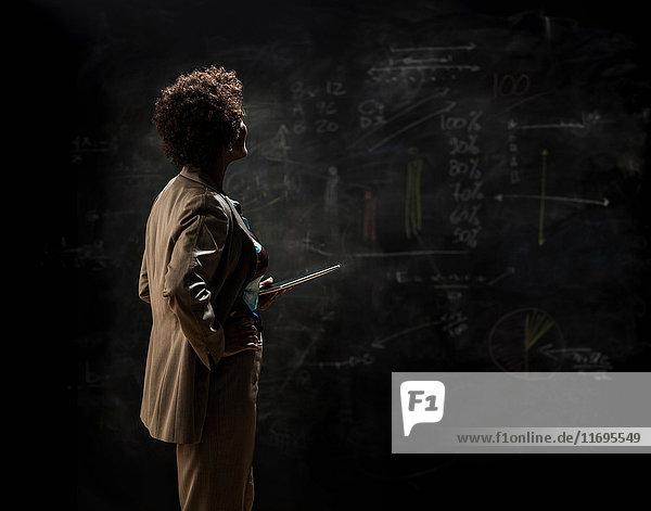 Woman looking at blackboard with digital tablet