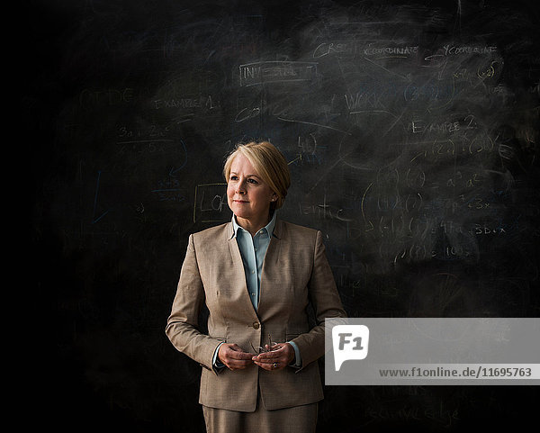 Portrait of businesswoman by blackboard