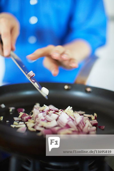 Close up of woman frying onions