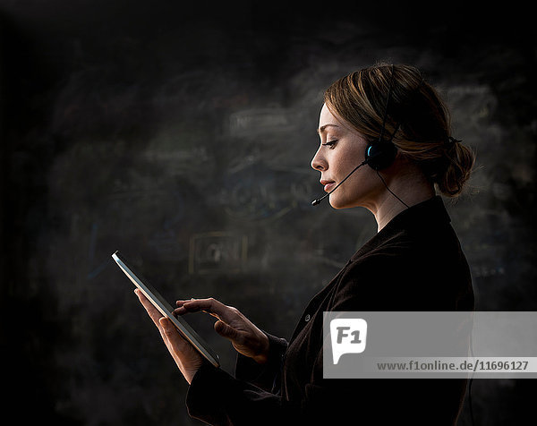 Businesswoman wearing telephone headset using digital tablet