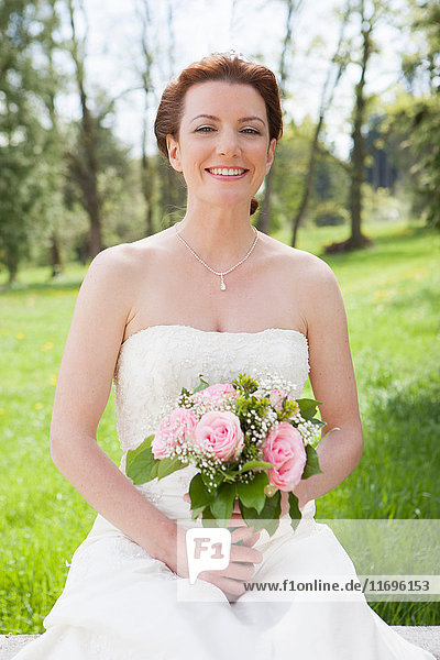 Lächelnde Braut mit Blumenstrauss an der Wand