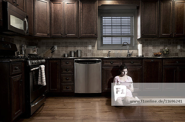 Woman in kitchen at night  using digital tablet