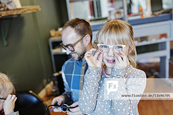 Portrait of girl wearing eyeglasses with family in workshop