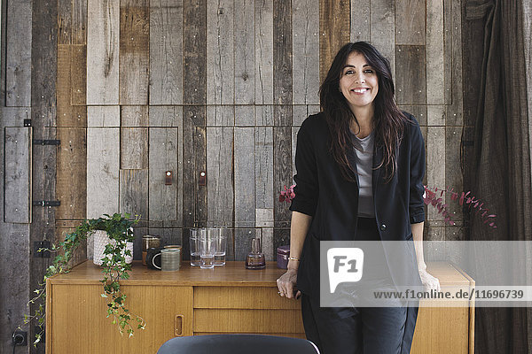 Porträt einer glücklichen Geschäftsfrau  die sich auf dem Sideboard gegen die Holzverkleidung in einem tragbaren Bürowagen stützt.