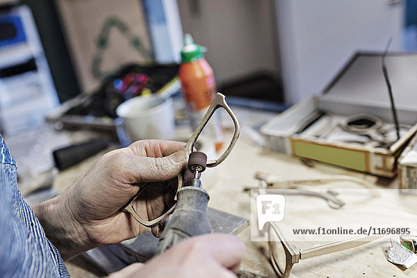 Abgeschnittenes Bild des Brillenherstellers mit Arbeitsgerät in der Werkstatt