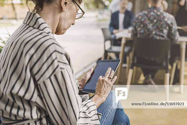 Senior Geschäftsfrau mit digitalem Tablett in tragbarem Bürowagen