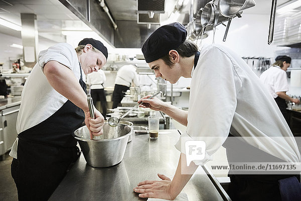 Side view of male chef students making food in commercial kitchen