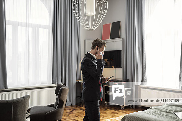 Side view of businessman talking on mobile phone while standing in hotel room
