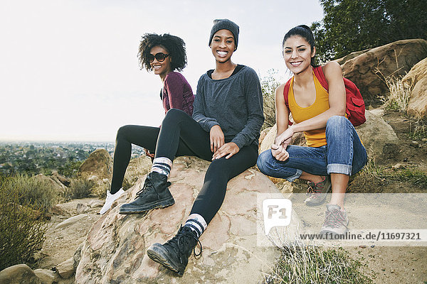 Portrait of smiling women sitting on rock