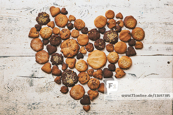 Verschiedene Kekse auf einem Holztisch in Herzform