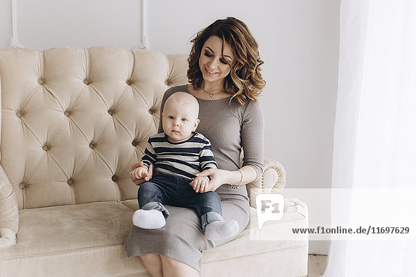 Portrait of Caucasian mother sitting on love seat with baby son