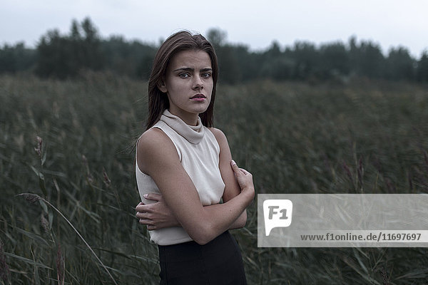 Caucasian teenage girl standing in field worrying