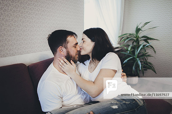 Kaukasisches Paar kuschelnd und küssend auf Sofa