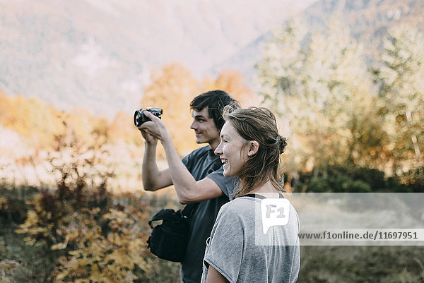 Kaukasisches Paar beim Fotografieren mit Kamera im Herbst