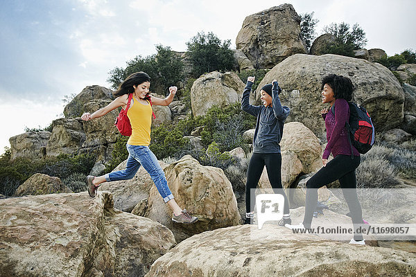Frauen jubeln einem Freund zu  der auf eine Felsformation springt
