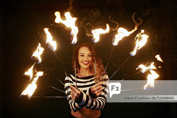 Kaukasische Frau  die nachts mit Feuer jongliert