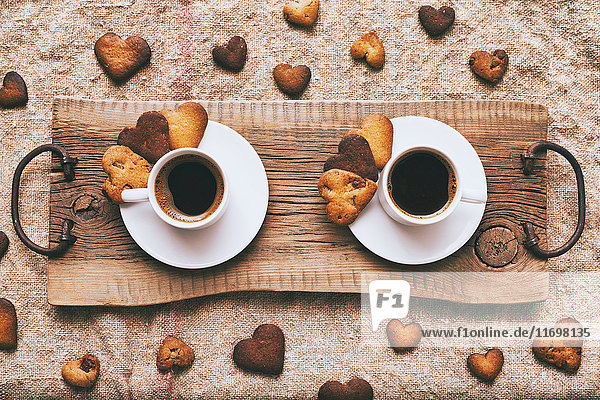 Kaffee und Kekse in Herzform auf einem Holztablett
