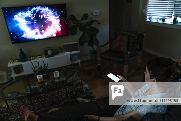 Woman watching television and using cell phone