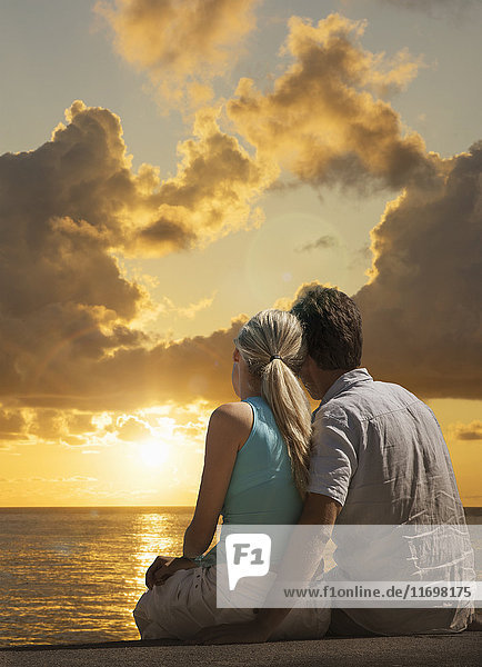 Caucasian couple admiring scenic view of sunset at ocean