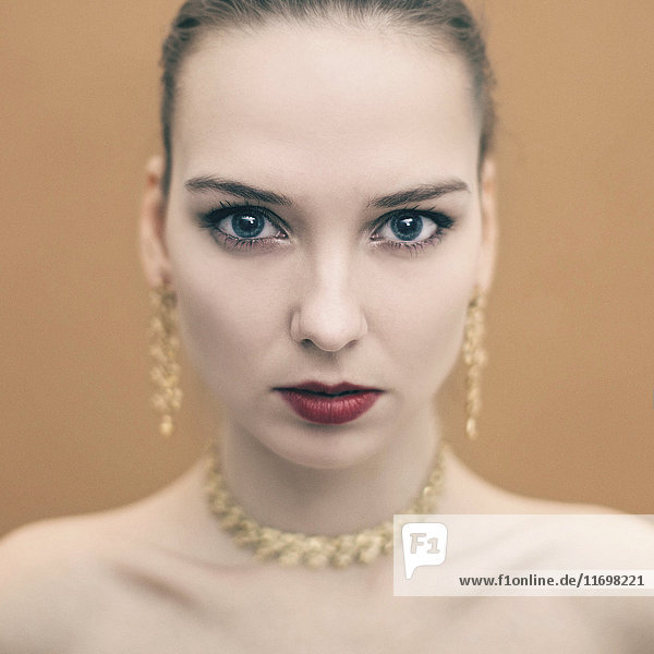 Porträt einer ernsten kaukasischen Frau mit Ohrringen und Halskette