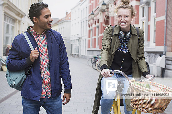 Junger Mann und Frau mit Fahrrad auf einer Stadtstraße
