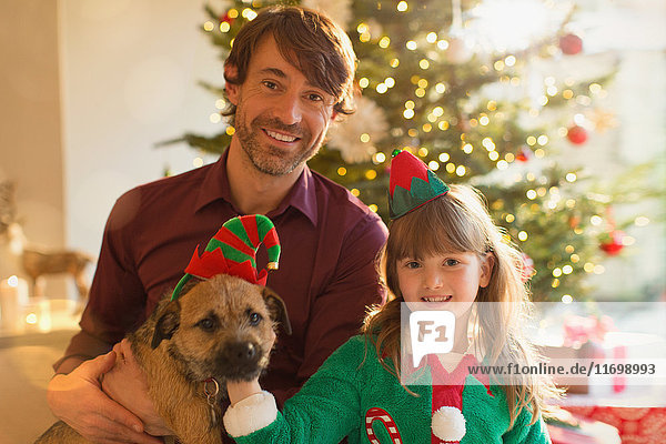 Portrait lächelnder Vater  Tochter und Hund vor dem Weihnachtsbaum