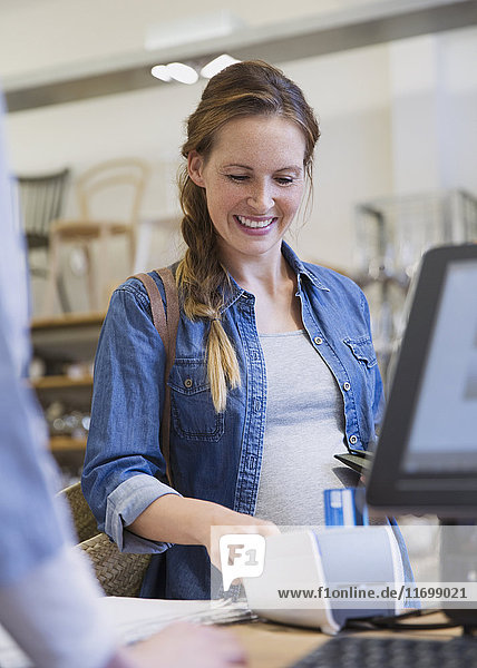 Smiling woman using credit card reader in shop
